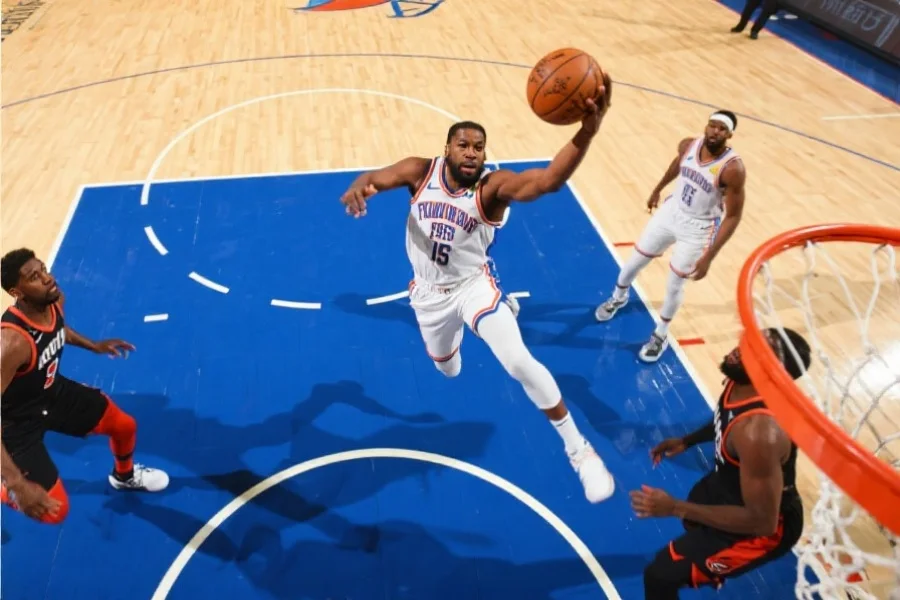 一位NBA球员在比赛中高速突破防守球员，飞身上篮得分，动作流畅且充满力量
